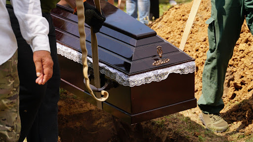 people carrying a coffin into a grave hole