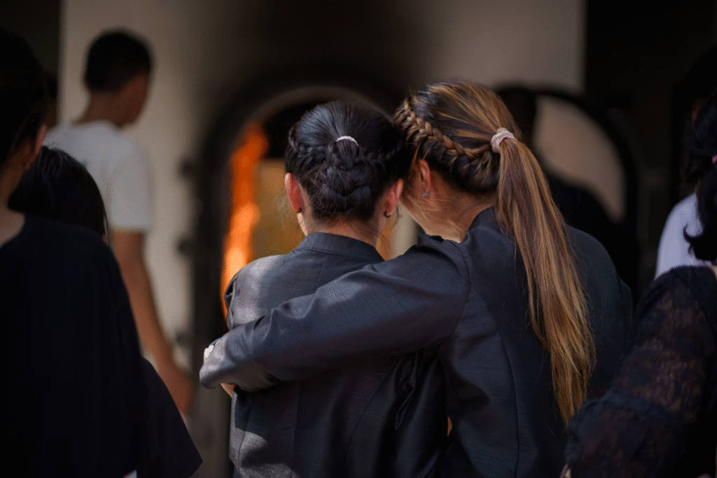two woman in black clothes hugging while grieving for their loved one